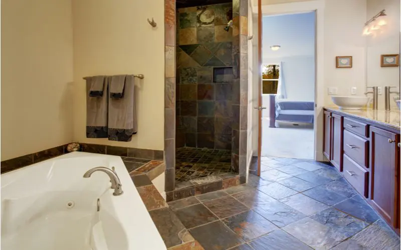 Tile shower idea in a bathroom with dark brown slate tile that covers the shower surround, shower floor, tub deck, and the rest of the floor