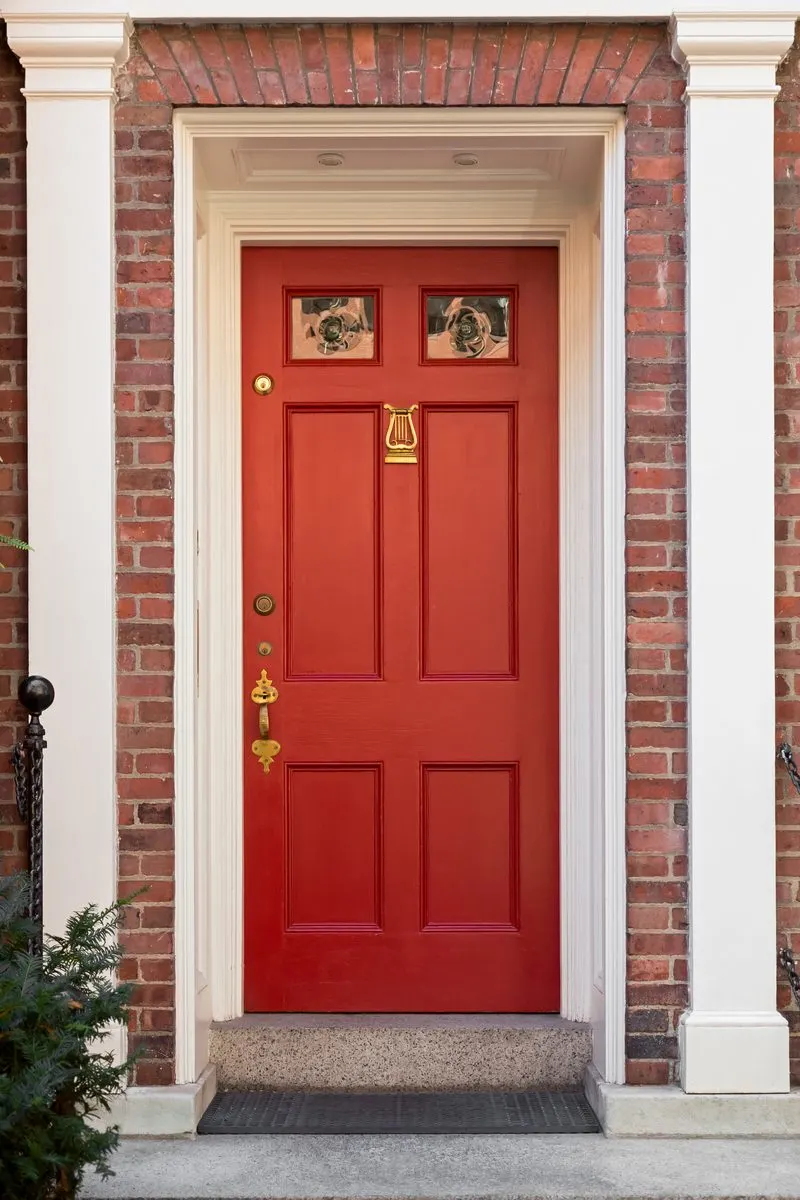 Red door idea with a white frame surrounding it nestled between white pillars