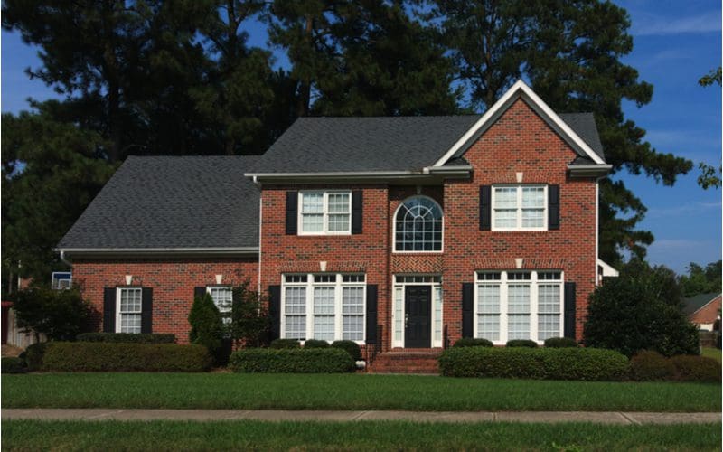 Example of the various types of siding featuring a brick sided home with big windows in the popular Colonial style