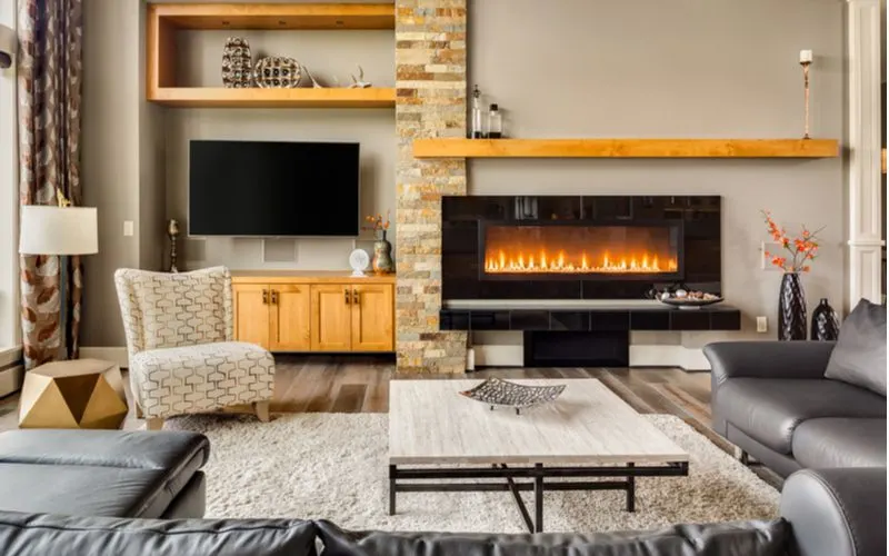Three natural wood floating shelves sit on the wall of a living room with fireplace