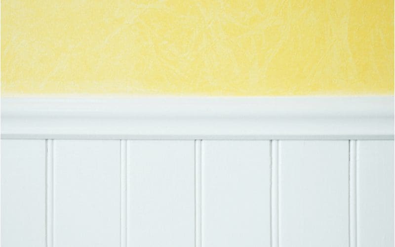 Wall painted bright yellow above a white wainscot half-wall