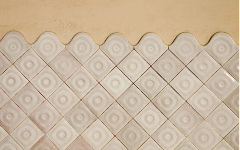 Diagonal white subway tile wainscoting below rounded top tiles