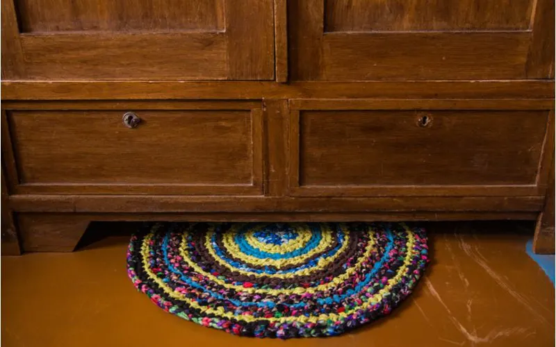 Mexican kitchen pictured with a colorful round rug below an old and unfinished wooden dining table