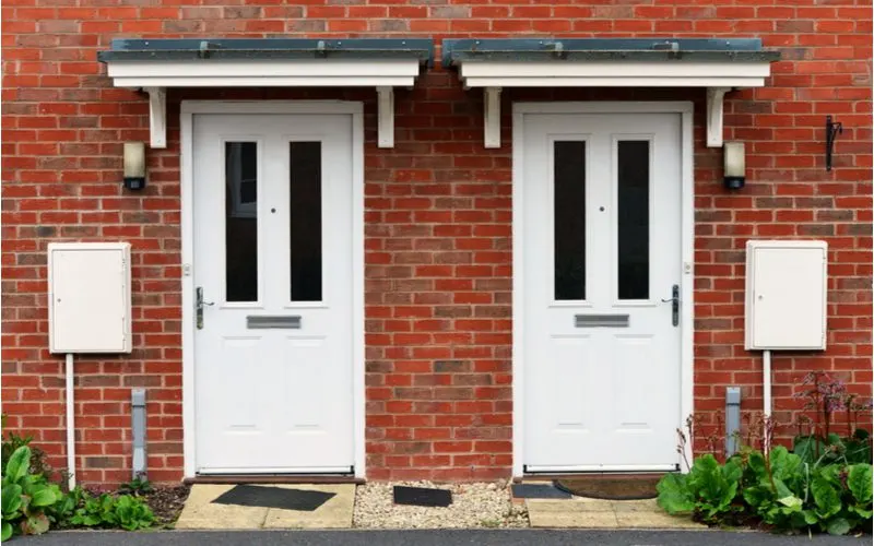 Side-by-side front doors painted white on a red brick house