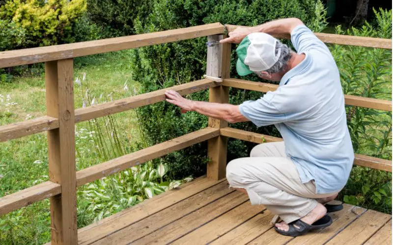 Horizontal slat deck railing idea with a man crouching in the foreground