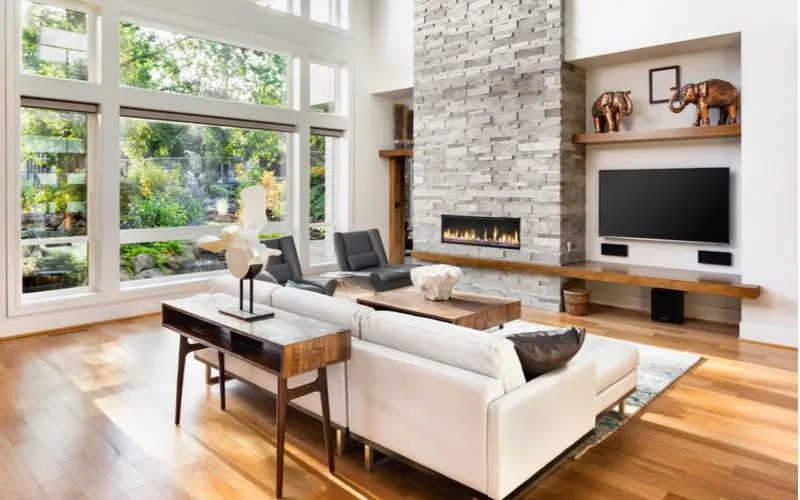 Big beautiful windows letting lot of natural light into a living room with a fireplace turned on