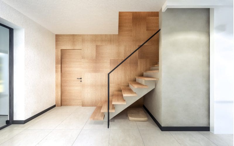 For a roundup on stair trim ideas, a plain metal railing with parquet wood paneling on the side