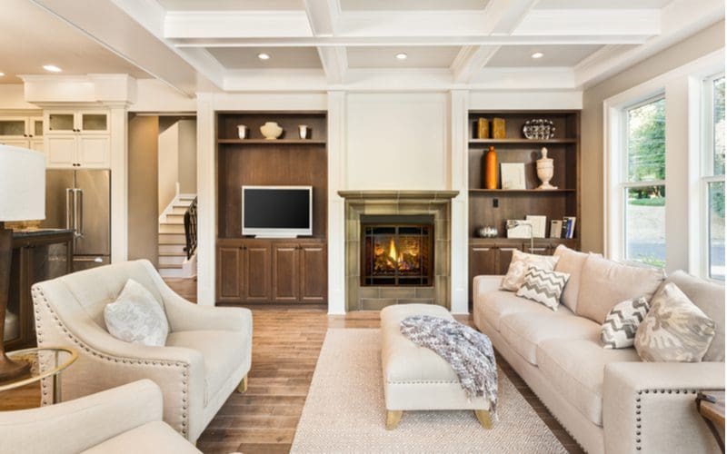 Living room with fireplace built for entertaining with lots of white furniture in the middle above a rug