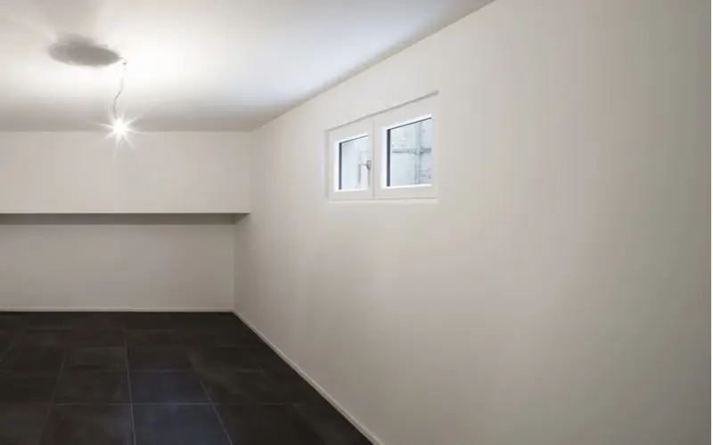 Tile basement flooring in dark color accented by bright white walls