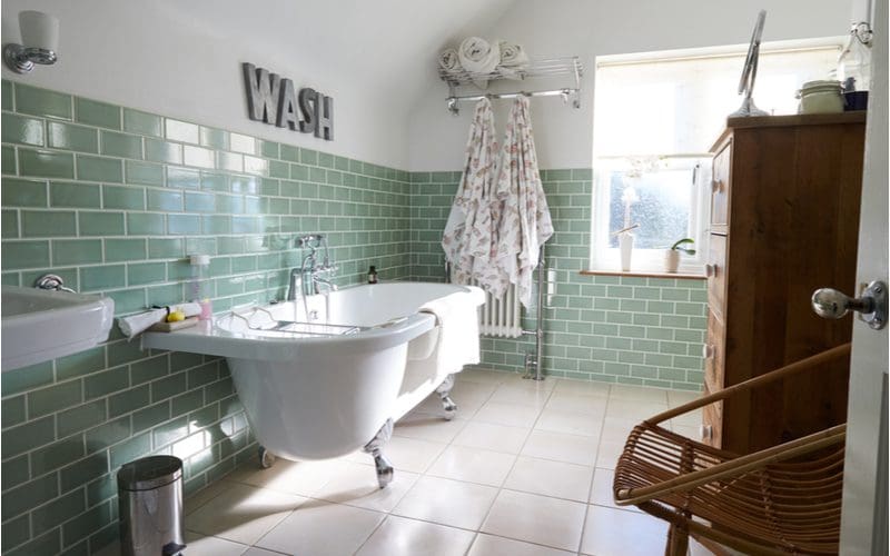 Contemporary green-tiled bathroom idea with a clawfoot tub with a big window in back