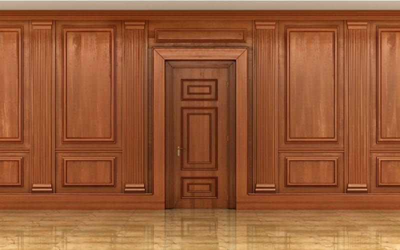 For a piece on how to paint wood paneling, a big wooden door sits in the middle of wood wood panels