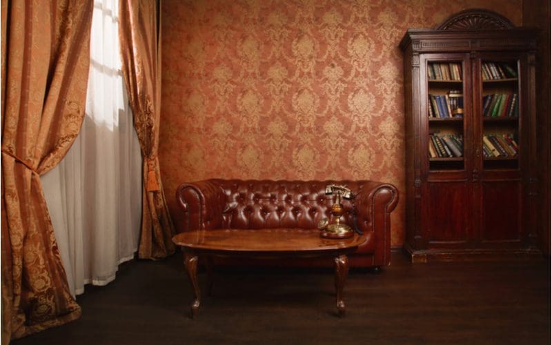 Almost-spooky Victorian style living room idea with a dark brown couch and curtains that are ominously parted to the side