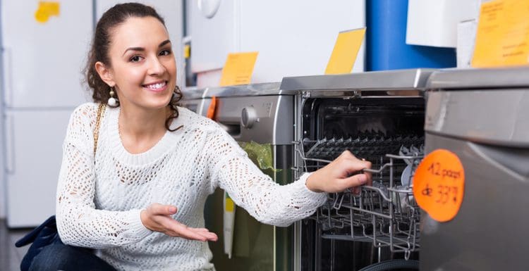 Featured image for a piece on standard dishwasher size, a woman putting her hand into a stainless unit