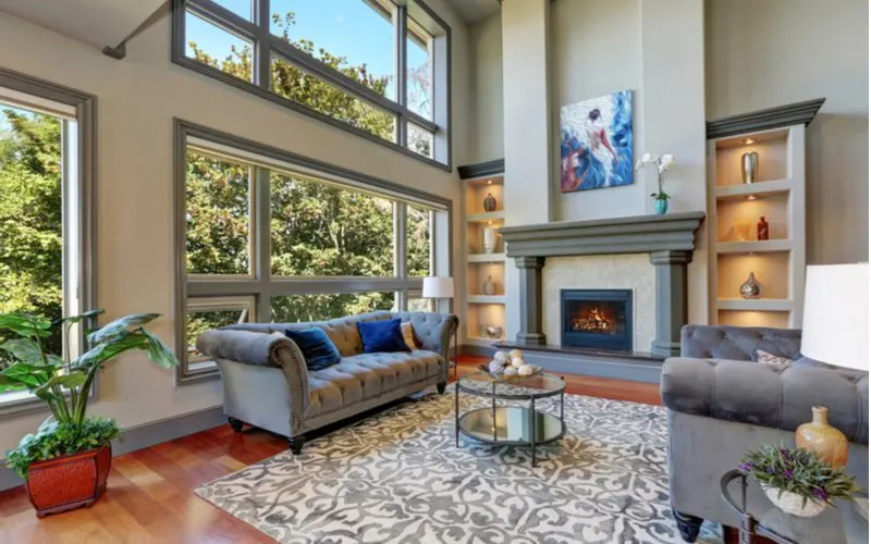 Paintings on the wall of a big living room with fireplace as the centerpiece with lots of light from big natural windows