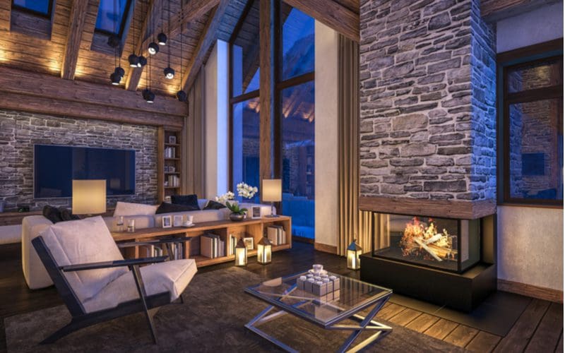 Lodge-inspired living room with fireplace next to gigantic picture windows that let incredible amounts of light in during the daytime