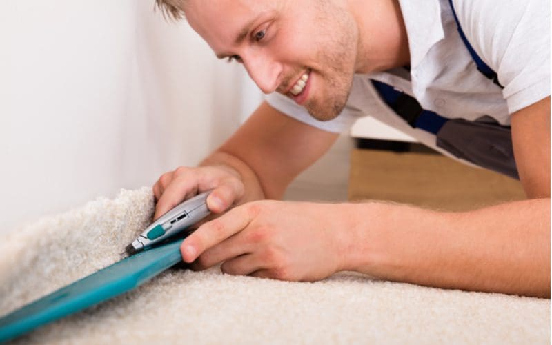 Piece on how to install carpet showing a guy cutting the end off a roll