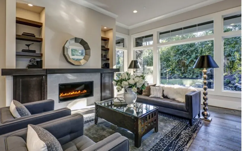 Metal accents all around in a living room with a fireplace snapped during the middle of the day and looking out onto a nice well-manicured and tree-enclosed yard