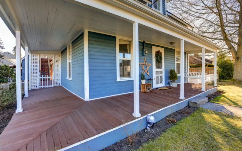 For a piece on front porch designs, a blue home featuring a big wraparound porch overlooking an expansive yard