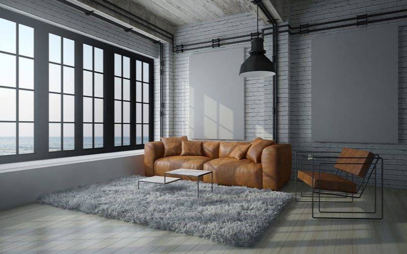 Dark brown couch living room idea with muted grey walls where the couch shows the pop of color 