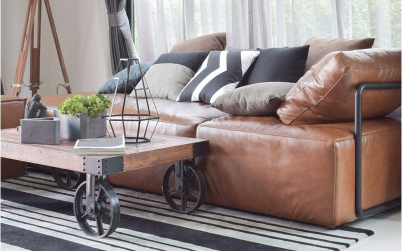 Brown faux leather couch in a living room with an industrial style