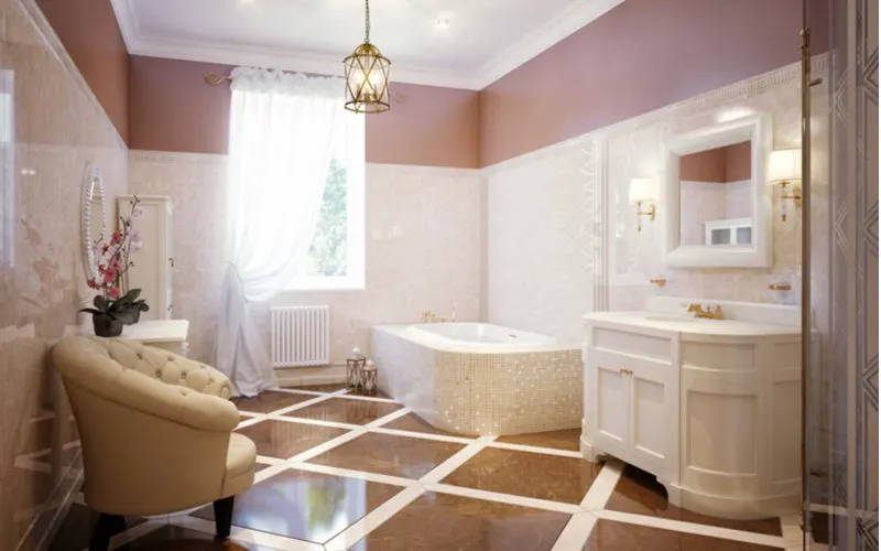 Classically modern bathroom idea with giant square floor tiles and a big white vanity with a sitting chair across the room