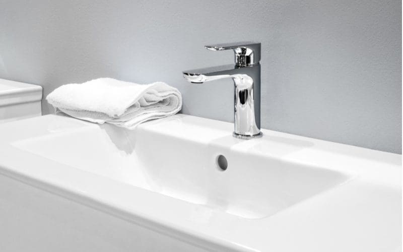 Bathroom faucet, one of the major parts of a sink, shown in chrome next to a towel