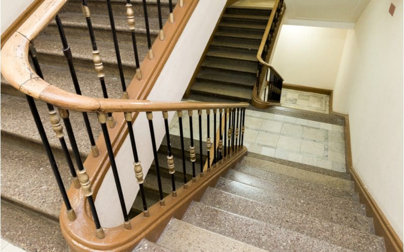 Stair trim idea featuring painted cement and gold accents with dark bronze and black balusters