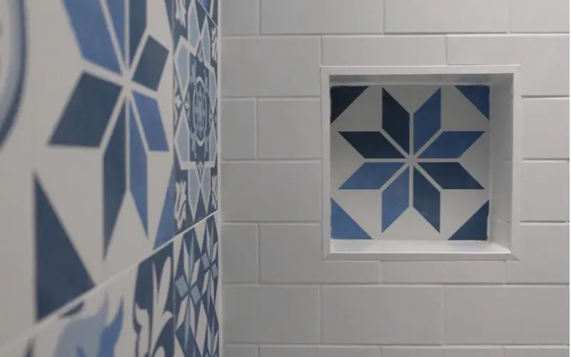 Tile shower idea with white subway tile on one wall and blue spanish-style tile on an accent wall and in the soap box