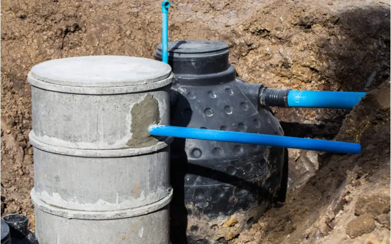 To help illustrate what a septic tank is, a concrete tank and a plastic tank sit next to each other in a big dirt hole