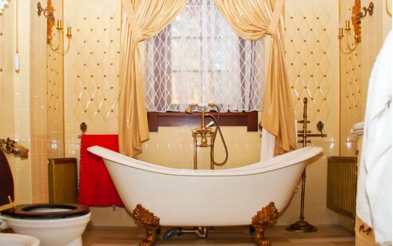 Luxury Boutique Bathroom idea in a yellow painted room with a white clawfoot tub with gold legs