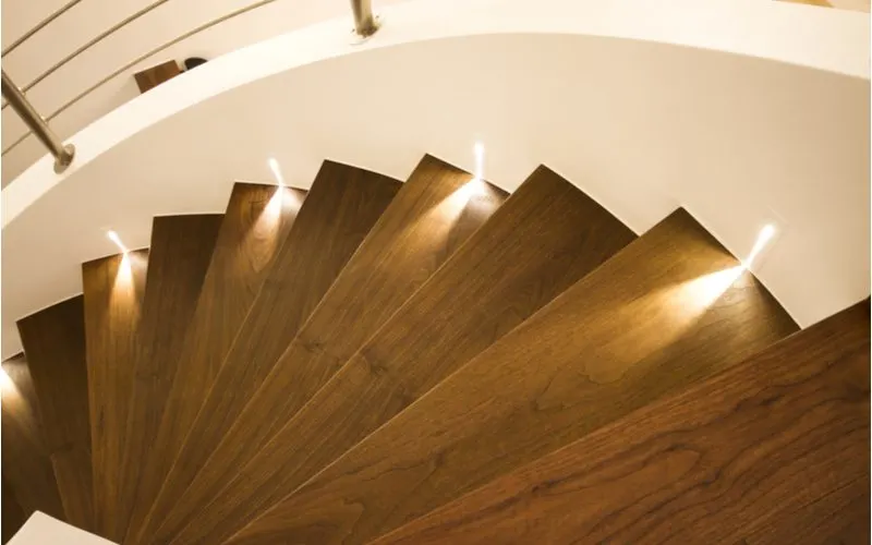 As an image for a piece on stair trim ideas, a brown staircase with plain white trim in which little footlights are found