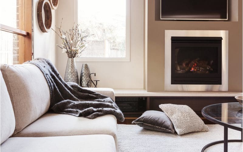 Warm comfy blankets draped on a couch next to a fireplace in a living room