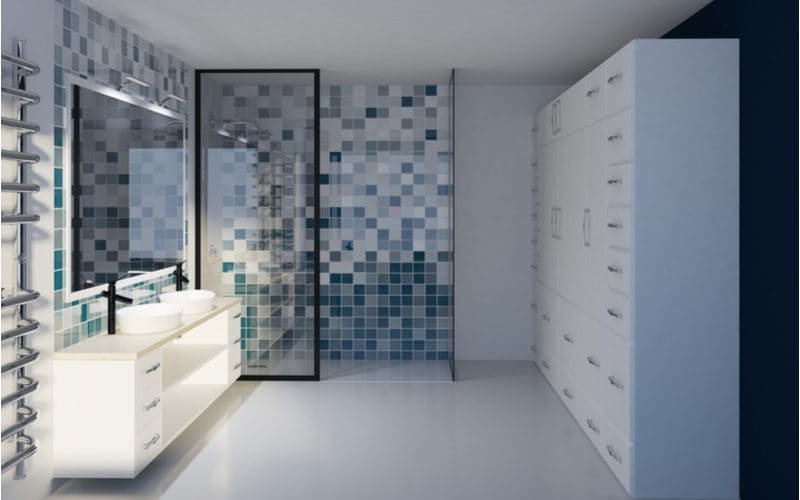 Tile shower idea with lots of blue and white square tiles put into a mosaic-style pattern in a white room with lots of drawers