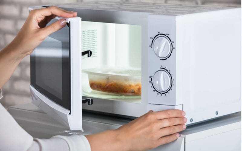 Woman closing a microwave door and pushing the open button