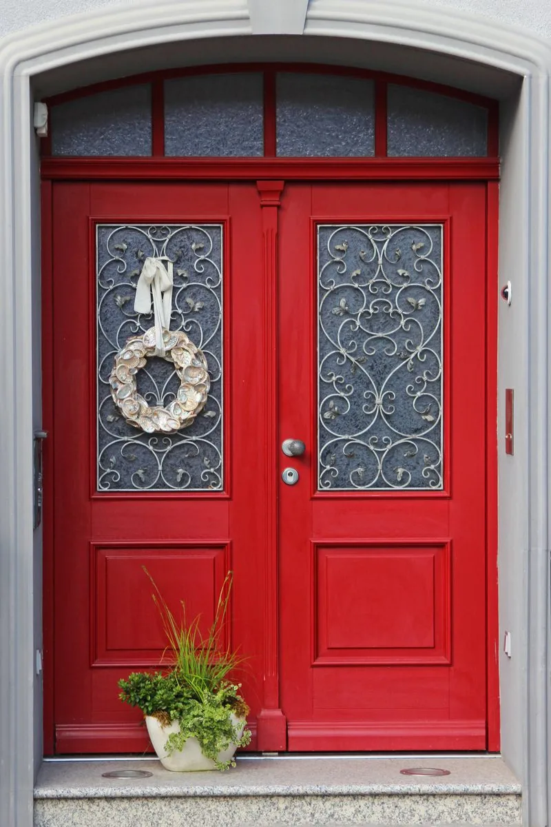 Double red door idea on a home with French doors and a big white wreath on the left door
