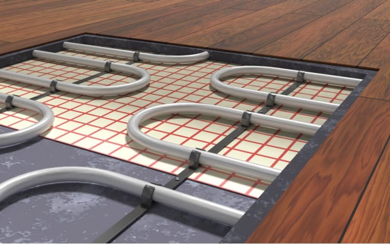 Hydronic floor heating system with pipes shown in a cutaway under wooden floors
