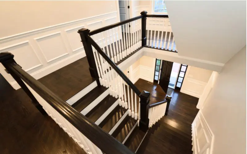 White wainscoting paneling with dark brown flooring with white balusters