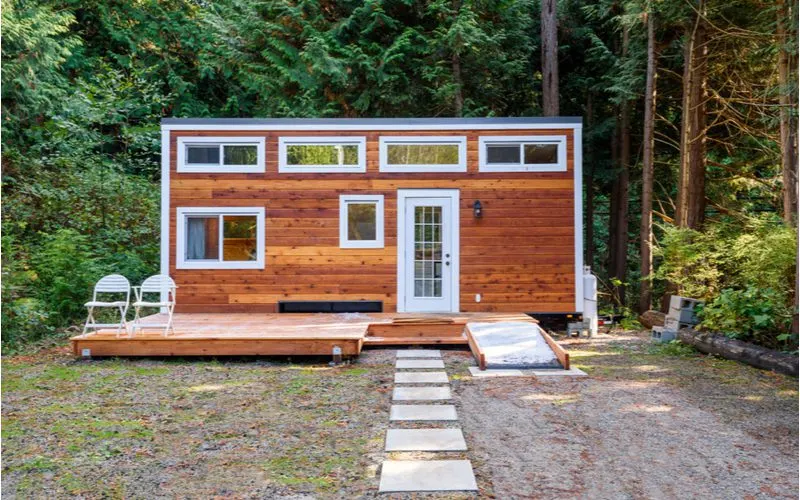 Image of a small wooden tiny house sitting outside a heavily forested backyard