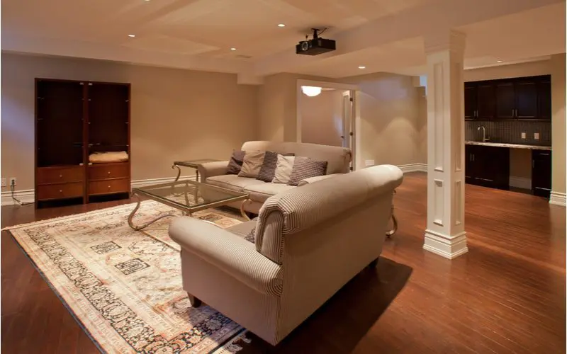 Go to the movies basement idea with a projector and an open-floorplan basement with wooden floors