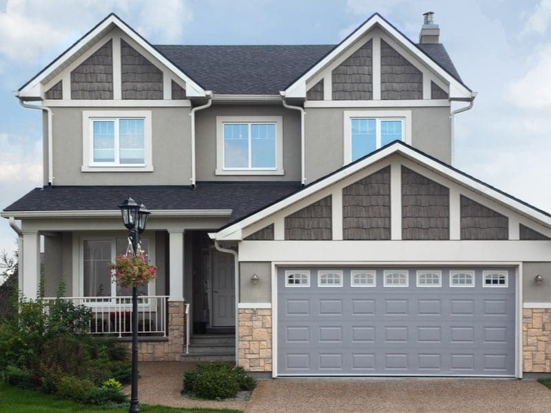 Grey Brick Cottage-Style House with a grey garage door and tan brick trim on the garage