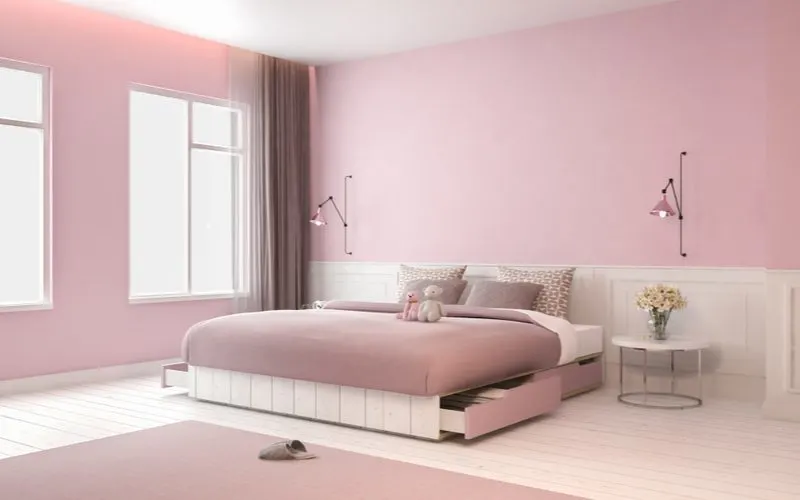 Vibrant pink aesthetic bedroom idea with light pink walls, a pink bedspread, pink rug, pink lamps, and white wooden floors with white wainscoting and a white bed frame and end table to match the flooring