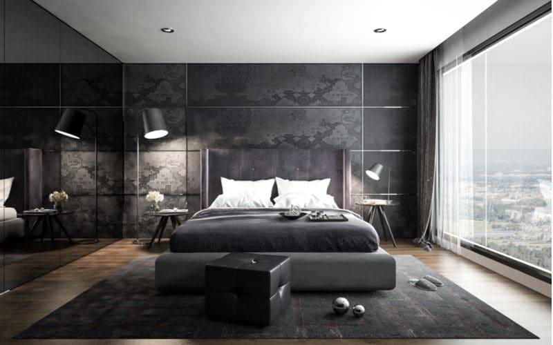Dark and modern men's room idea with dark grey wallpapered walls with chrome square trim alongside a giant lamp on the left side of the bed
