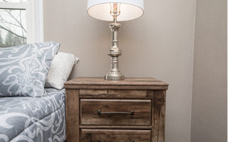 A classy mens bedroom idea featuring rustic-looking side lamps on a stained wooden end table