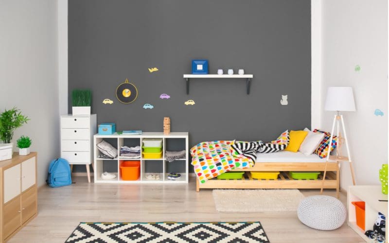 Grey kids bedroom idea with a large grey chalkboard wall in front of a bed and storage cubby
