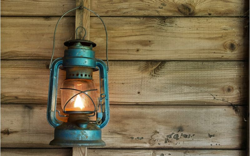 A storm lantern hangs on the vertical wooden support of a cabin wall in a photo as an idea for a mens bedroom