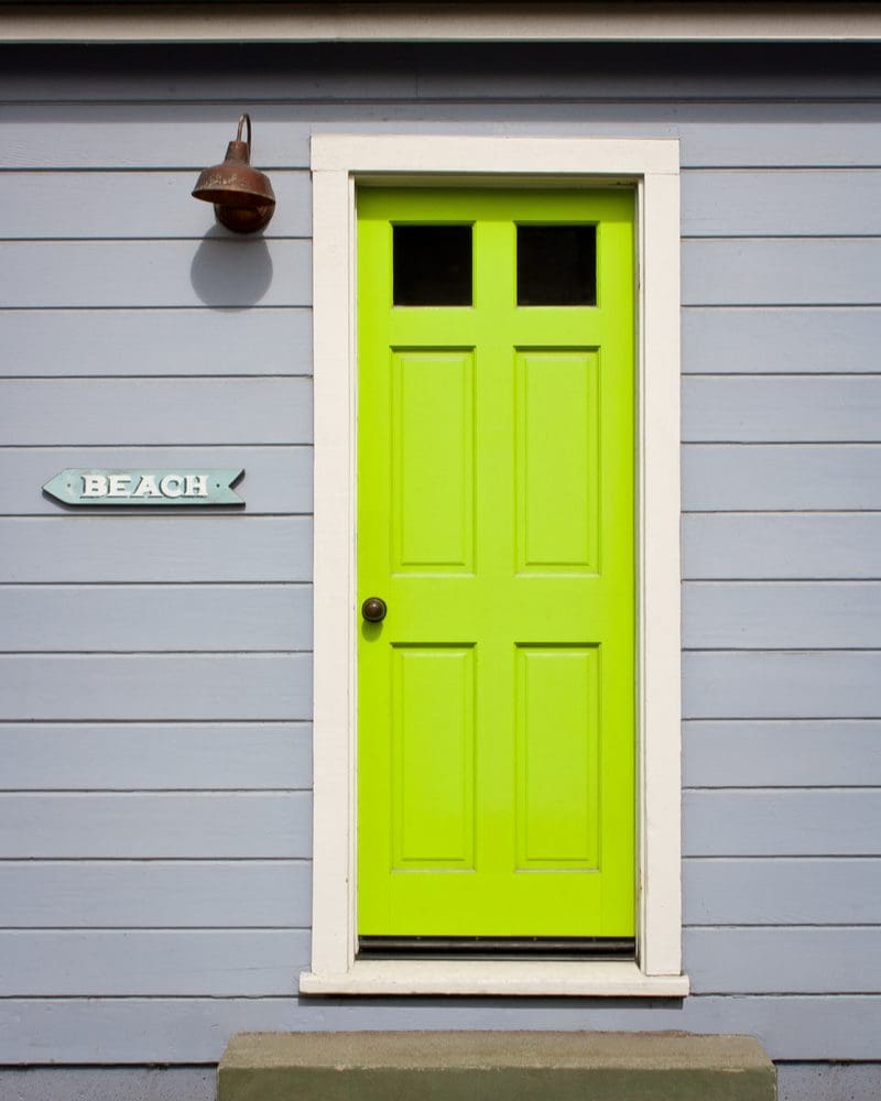 Gray house with lime green door and white trim as an idea for a front door color for a gray house