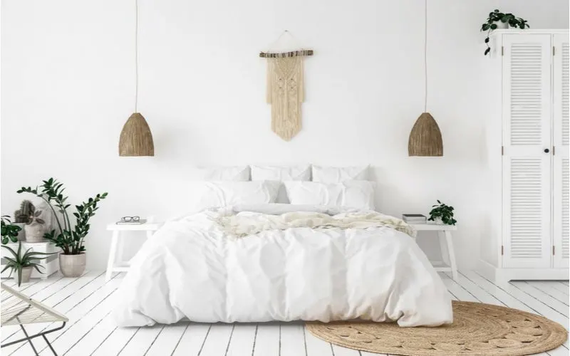 Scandi-boho bedroom idea featuring lots of natural woods as accents in an otherwise white room with white floors, white walls, and white bed linens and furniture