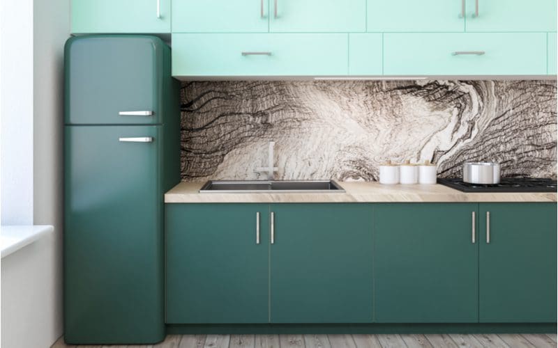 To help answer what color kitchen cabinets go with gray floors, a kitchen with granite swirly backsplash and gray floors has green painted cabinets