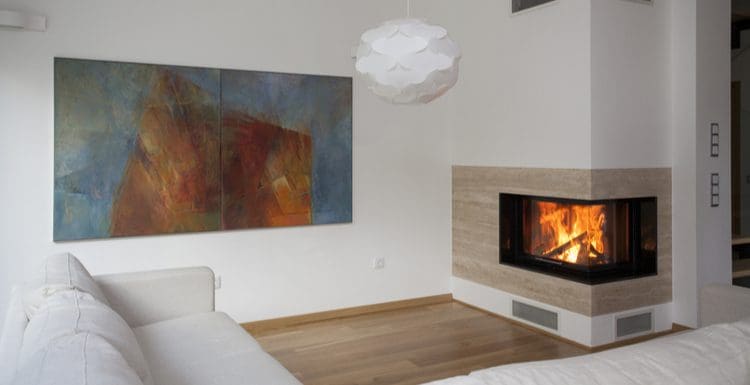 Featured image for a roundup titled Fireplace Tile Ideas showing a modern fireplace with 2 glass sides in the corner of a wall