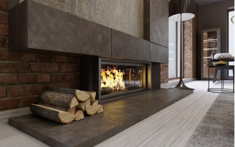 Gas fireplace without any tile on the surround that has a pile of wood next to it for decoration